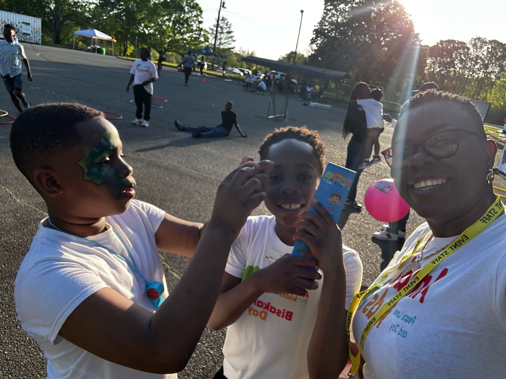 Children with painted faces and staff member smiling warmly at Bisakana Day
