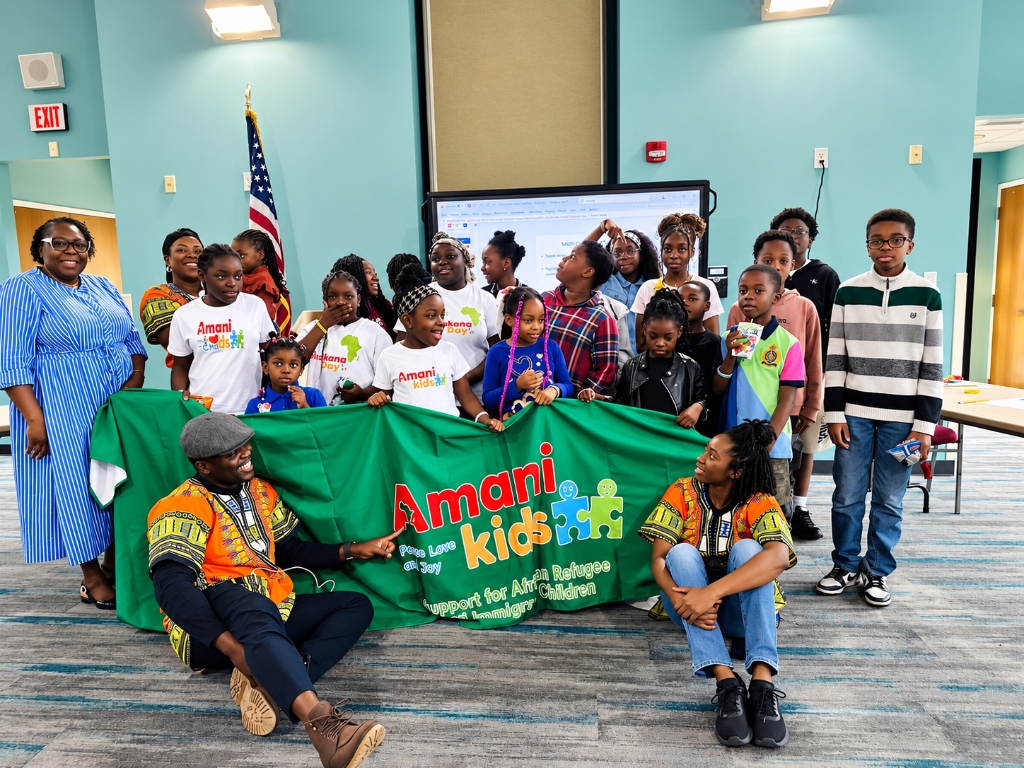 Amani Kids community — youth, children, and mentors holding the green Amani Kids banner in Charlotte, NC